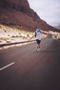 Traveler with backpack standing in the center of an epic winding road. Huge volcanic mountains in the distance behind