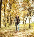 Traveler backpacker walking in autumn forest, young caucasian man in gray jacket goes along the trail admiring beauty of