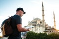 A traveler in a baseball cap with a backpack is looking at the map next to the blue mosque - the famous sight of Royalty Free Stock Photo