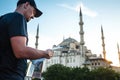 A traveler in a baseball cap with a backpack is looking at the map next to the blue mosque - the famous sight of Royalty Free Stock Photo