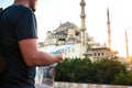 A traveler in a baseball cap with a backpack is looking at the map next to the blue mosque - the famous sight of Royalty Free Stock Photo