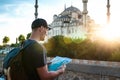 A traveler in a baseball cap with a backpack is looking at the map next to the blue mosque - the famous sight of Royalty Free Stock Photo