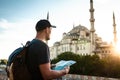 A traveler in a baseball cap with a backpack is looking at the map next to the blue mosque - the famous sight of Royalty Free Stock Photo