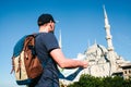 A traveler in a baseball cap with a backpack is looking at the map next to the blue mosque - the famous sight of Royalty Free Stock Photo