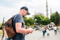 A traveler in a baseball cap with a backpack is looking at the map next to the blue mosque - the famous sight of Royalty Free Stock Photo