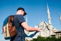 A traveler in a baseball cap with a backpack is looking at the map next to the blue mosque - the famous sight of Royalty Free Stock Photo