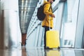 Traveler in bright jacket with yellow suitcase backpack at airport on background large window blue sky, passenger waiting flight Royalty Free Stock Photo