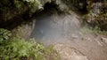 Traveler descends into cave. Stock footage. Explorer with insurance goes down steep descent into dark foggy cave in rock