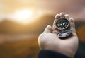 Traveler explorer man holding compass in a hand in mountains at sunrise, point of view Royalty Free Stock Photo