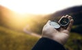 Traveler explorer man holding compass in a hand in mountains at sunrise, point of view