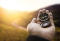 Traveler explorer man holding compass in a hand in mountains at sunrise, point of view