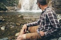 Traveler Explorer Sitting And Looks On Waterfall. Travel Hiking Destination Experience Lifestyle Concept