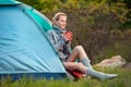 Traveler Girl with a cup of tea resting near a tent against gree Royalty Free Stock Photo