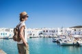 Traveler girl enjoying vacation in Greece. Young woman wearing hat looking at greek village with sea. Summer holidays, vacations,
