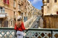 Traveler girl on iron bridge looking historic buildings in city centre of Valletta, Malta Royalty Free Stock Photo