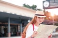 Traveler girl with map, hat and backpack walking train on railway platform.