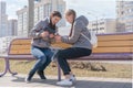 Girl pouring tea from thermos to cup sitting with girlfriend on wooden city bench Royalty Free Stock Photo