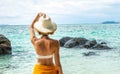 Traveler girl relaxing on a tropical beach, in nature. Summer vacations. Back view of beautiful woman in swimsuit and hat spending Royalty Free Stock Photo