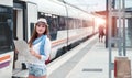 Traveler girl waiting and boarding a train on railway platform. Royalty Free Stock Photo