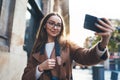 Traveler in glasses self cellphone internet technology in europe trip. Tourist girl taking photo selfie on smartphone online