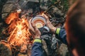 Traveler hand with big mug of hot tea near campfire