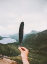 Traveler hand holding feather in mountains Traveling alone