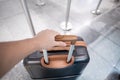 Traveler hand holding suitcase in an airport. Royalty Free Stock Photo