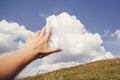 Traveler hand reaching out to mountains and sky clouds. focus on