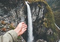 Traveler hand showing waterfall travel in Norway