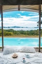 Traveler hat, hot tea cup and teapot on white bed against Beautiful ocean view background, Tourists relaxing in tropical resort Royalty Free Stock Photo