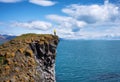 Traveler on the high rocks in Iceland. Travel and adventure. Rocks and ocean. Natural landscape at the summer time. Royalty Free Stock Photo