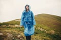 Traveler hipster girl smiling in blue raincoat with backpack, ex