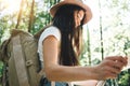 Traveler hipster woman with backpack and hat hold in hands location map and searching directional among trees in forest