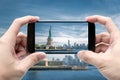 Traveler holding smartphone to take a photo of The Statue of Liberty Royalty Free Stock Photo