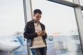 Traveler inside airport terminal. Young man using mobile phone and waiting for his flight. Royalty Free Stock Photo