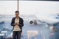 Traveler inside airport terminal. Young man using mobile phone and waiting for his flight. Royalty Free Stock Photo