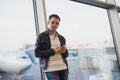 Traveler inside airport terminal. Young man using mobile phone and waiting for his flight. Royalty Free Stock Photo