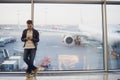 Traveler inside airport terminal. Young man using mobile phone and waiting for his flight. Royalty Free Stock Photo