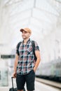 Traveler is late at the train station. Young man with backpack and suitcase missed the train and waiting for next Royalty Free Stock Photo