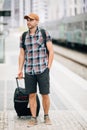 Traveler is late at the train station. Young man with backpack and suitcase missed the train and waiting for next Royalty Free Stock Photo