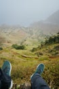 Traveler legs over verdant valley lead to ocean coastline. Santo Antao Island, Cape Verde