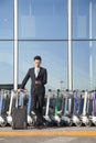 Traveler looking at cellphone next to row of luggage carts Royalty Free Stock Photo