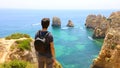 Traveler man with backpack enjoying and relaxing in front of stunning view in Southern Portugal. Back view of traveler male