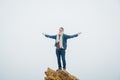 Traveler man with a backpack standing on top of mountain top with hands raised in the air. Success and risk concept. Place for Royalty Free Stock Photo