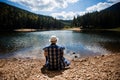 Traveler man in hat relaxing meditation with serene view mountains and lake landscape. Travel lifestyle hiking concept Royalty Free Stock Photo