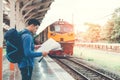 Traveler man with map and waits train on railway platform