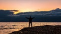 Traveler on a rocky seashore at dramatic sunrise time