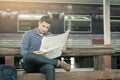 Traveler man sitting at train station and looking on map for travel planning. Royalty Free Stock Photo