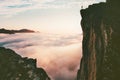 Traveler man standing on the edge cliff over clouds