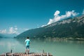 Traveler man standing on the lake wooden pier. Scenic views of the lake and rocky coast.